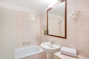 Un baño con bañera, lavamanos y espejo.