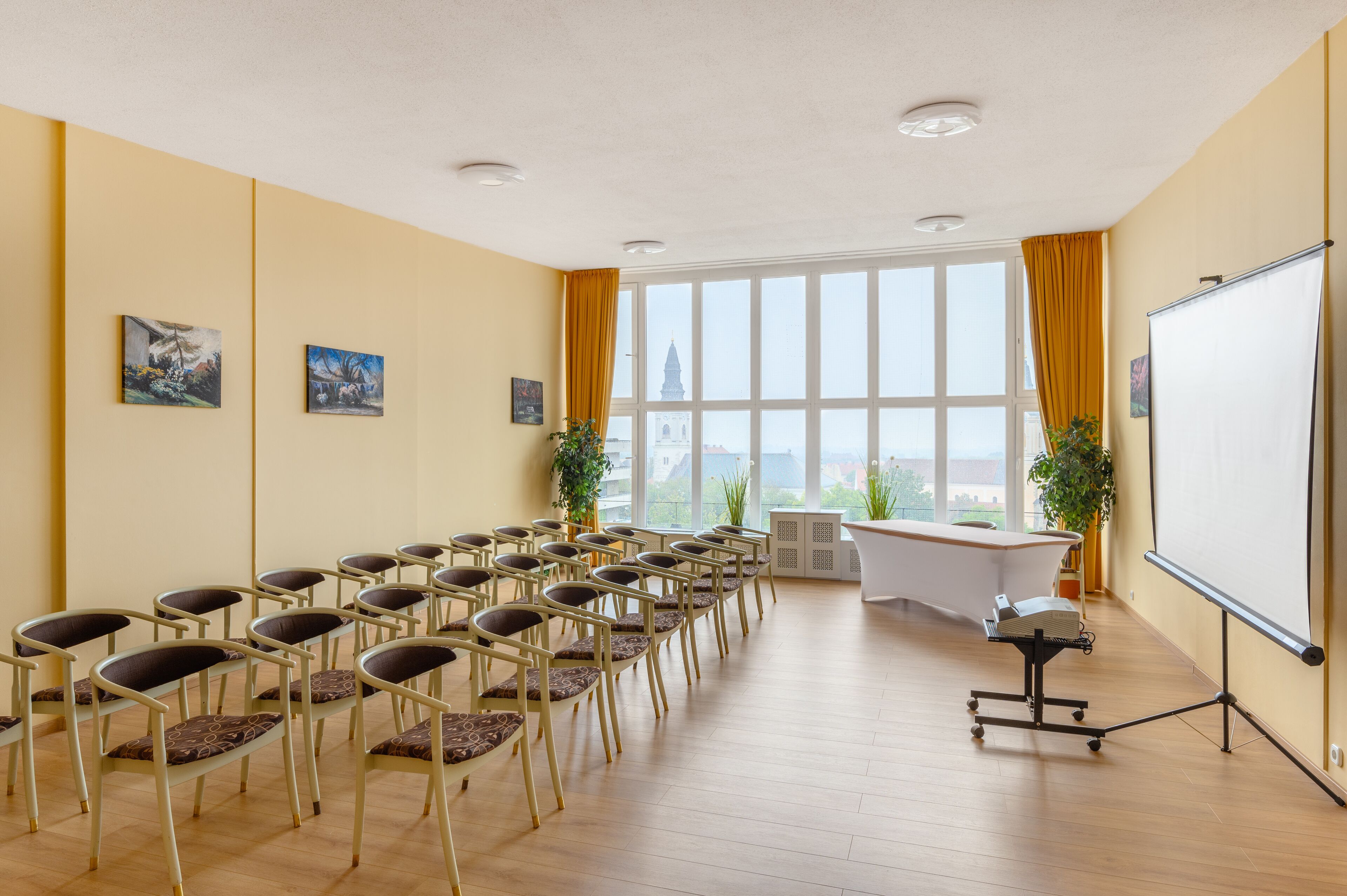 Un salón de conferencias con filas de sillas, una pizarra y un amplio ventanal con cortinas.