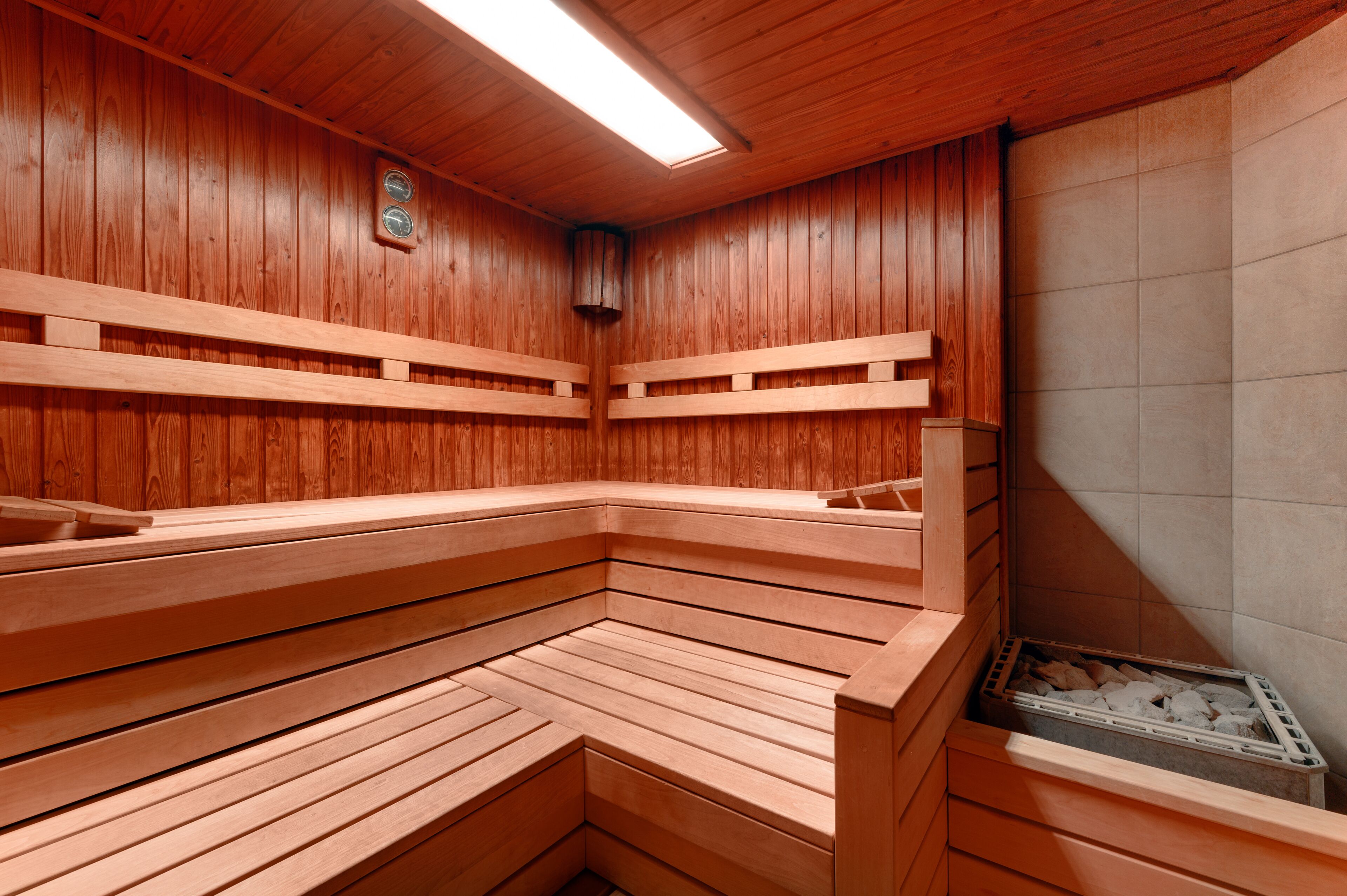 A sauna with wooden benches and a tiled wall.