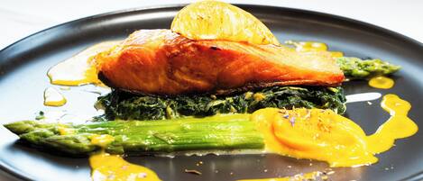 A plate of food with salmon, asparagus, and a lemon slice.