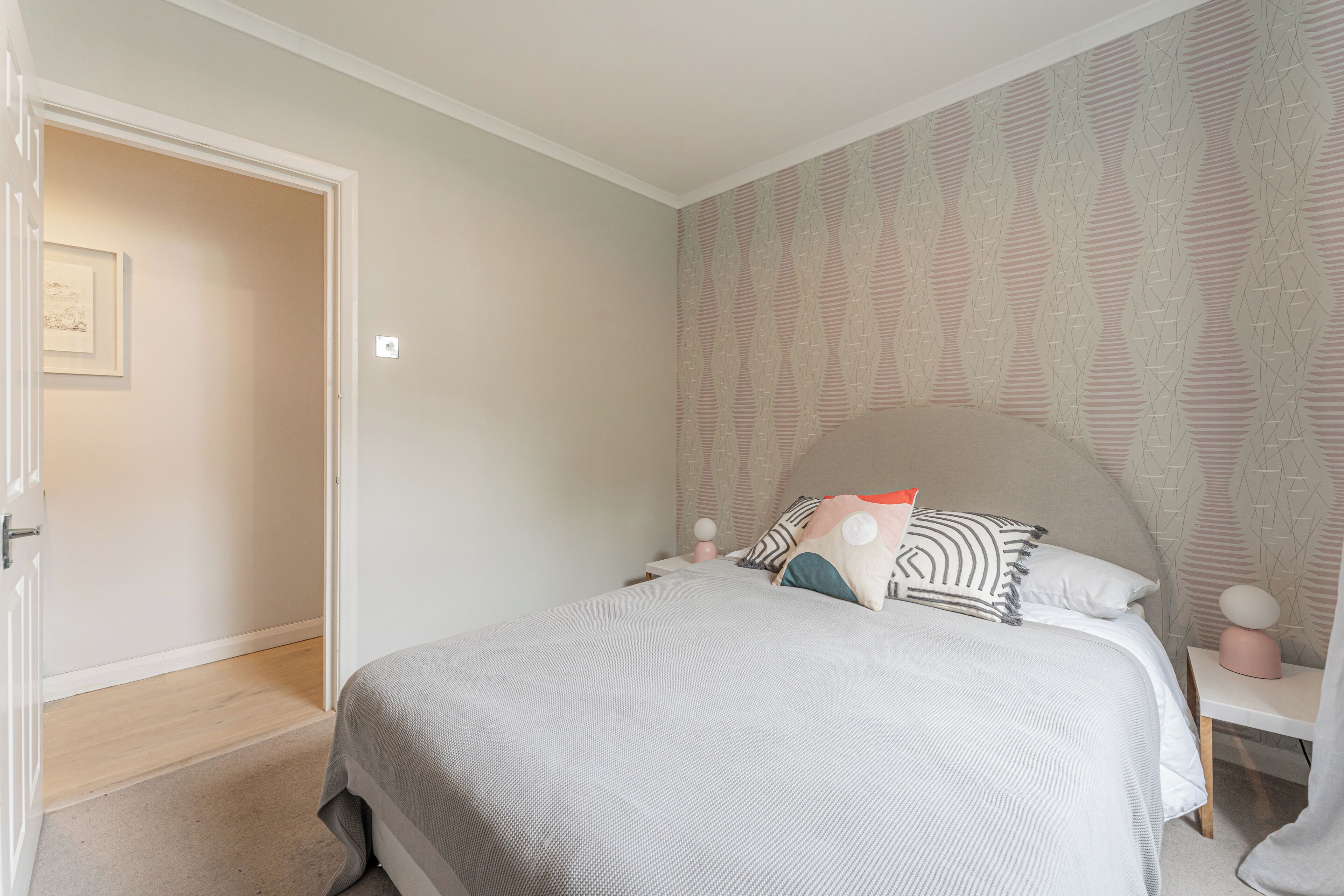 A bedroom with a bed, bedside tables, and a patterned wallpaper.
