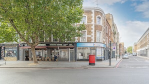 A street view with a building featuring a corner shop and a coffee shop. - King’s Cross Charm (London)