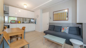 A compact living space with a kitchenette, a dining area, and a seating area with a sofa and a coffee table. - King’s Cross Charm (London)