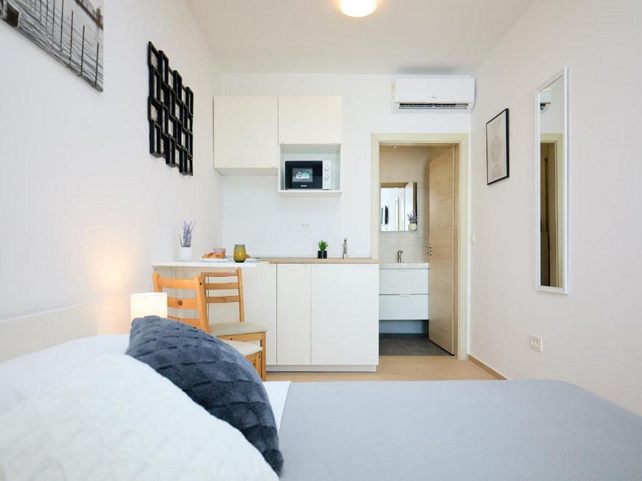 Une chambre compacte comprenant un lit, un petit bureau et une kitchenette.