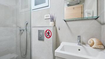 A modern bathroom with a shower, toilet, and sink.