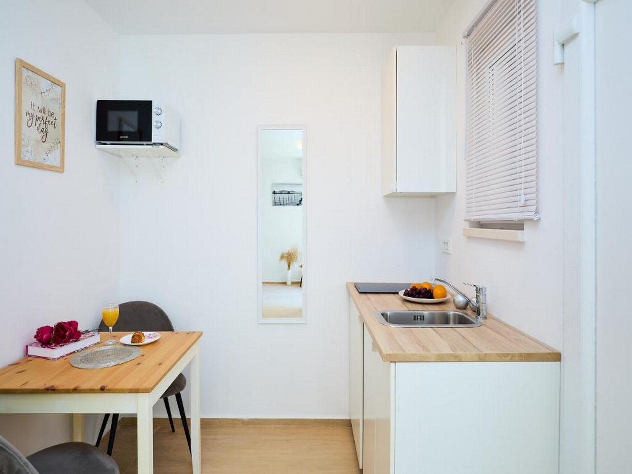 A compact kitchenette with a microwave, a sink, and a small dining area with a table and chairs.