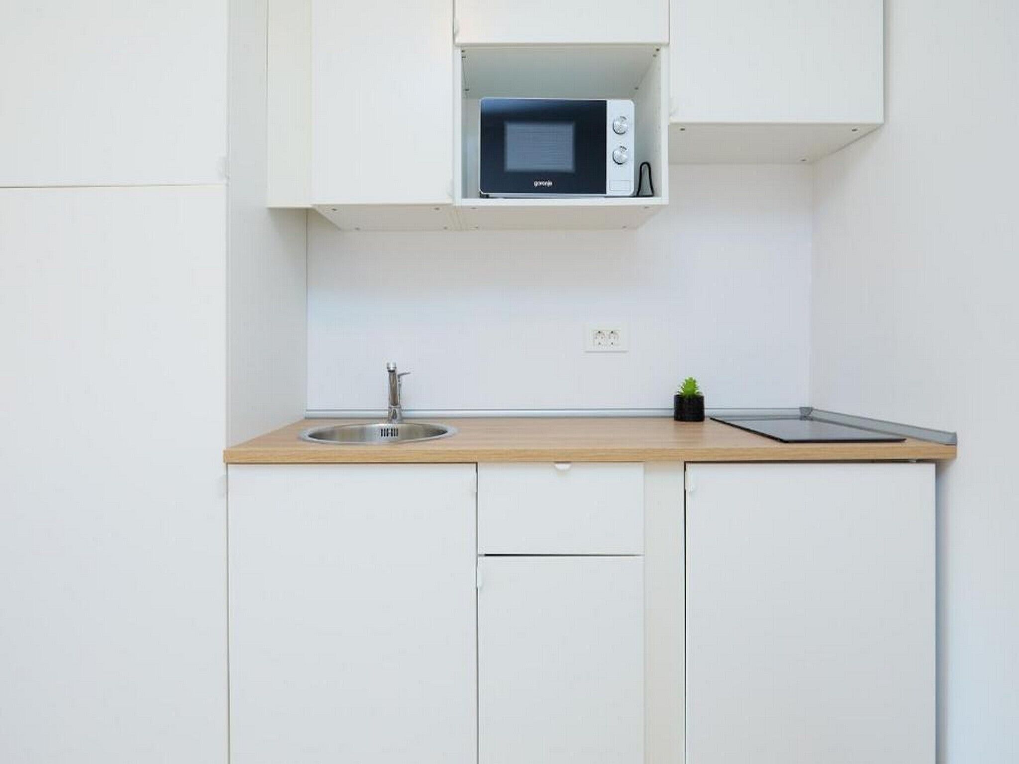 Une cuisine compacte équipée d’un four à micro-ondes, d’un évier et d’un petit plan de travail.