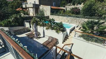 A rooftop pool area with lounge chairs and a stone wall.