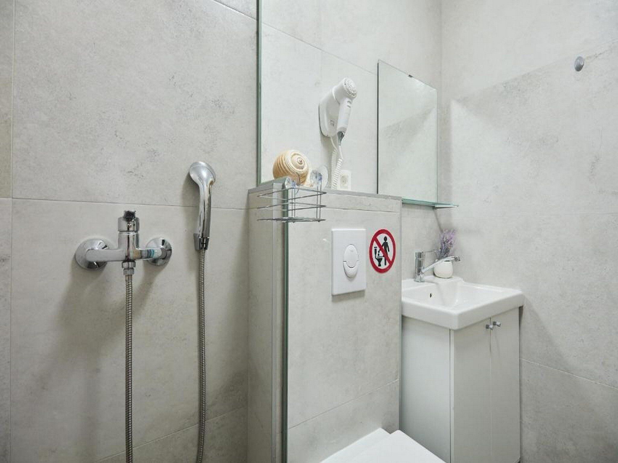 A modern bathroom with a shower, a hairdryer, and a sink.