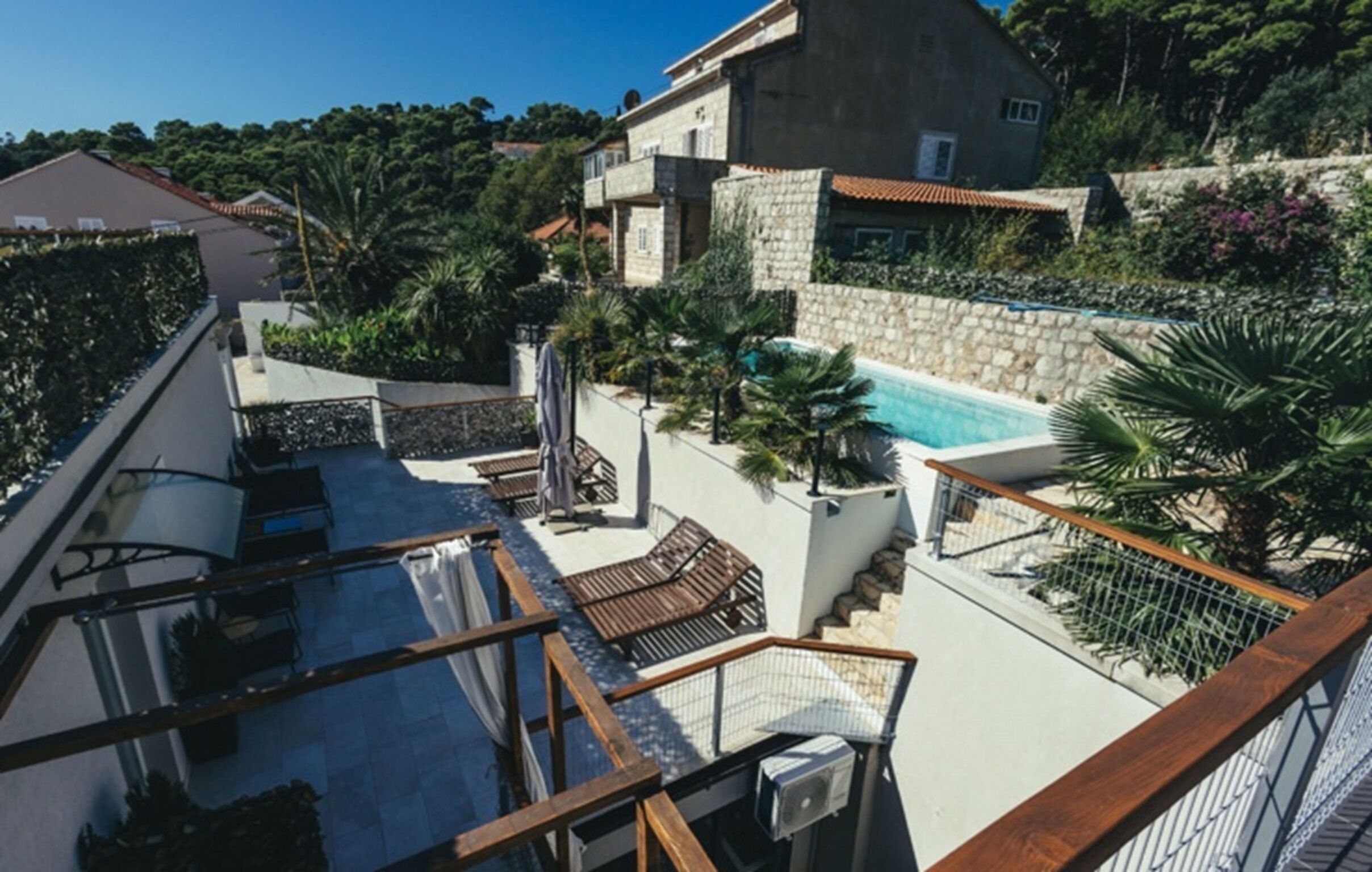 A residential property with a swimming pool, outdoor seating, and a staircase leading to a rooftop area.