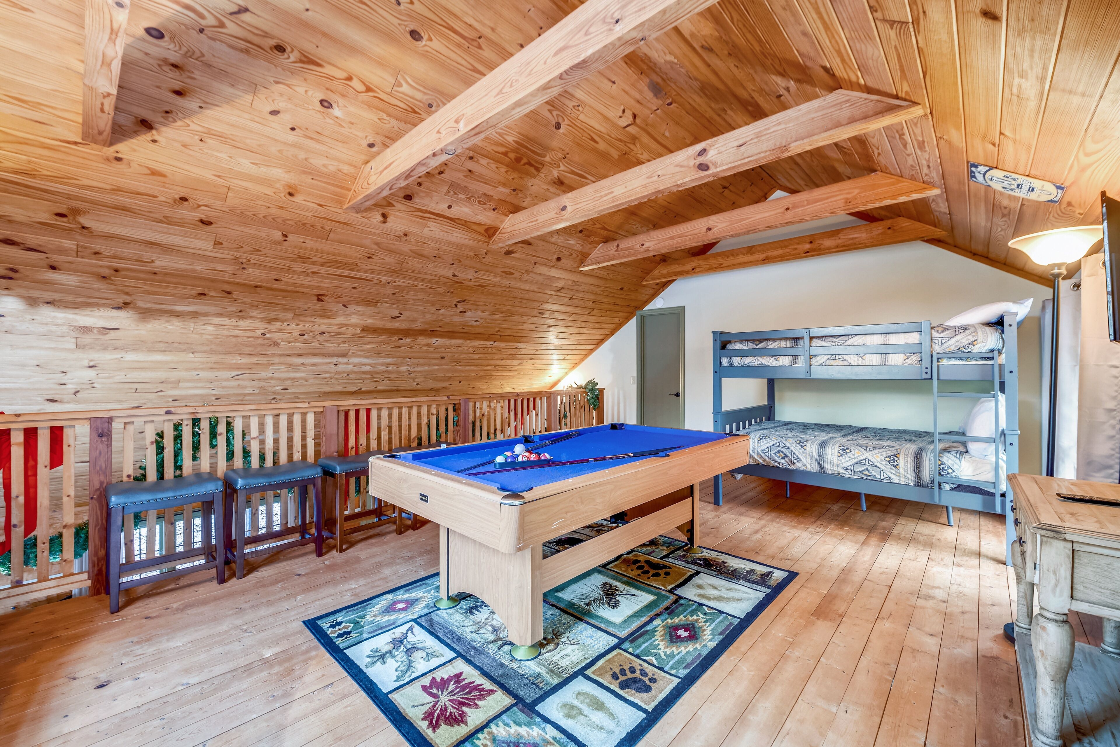 Un soffitto in legno con travi a vista, un biliardo e un letto a castello in una stanza con pavimento di legno.