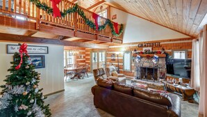 Een gezellige woonkamer met een open haard, een kerstboom en een balkon versierd voor de feestdagen.