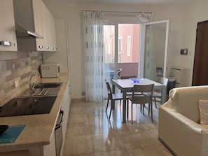 Cozinha compacta com pia, micro-ondas e área de refeições com mesa e cadeiras.