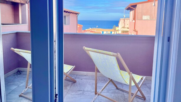 A balcony with two folding chairs, a view of the sea, and buildings in the background. - New Construction,  Luxury 2 bed apartment facing the sea, internet wi-fi, aircon (La Ciaccia)