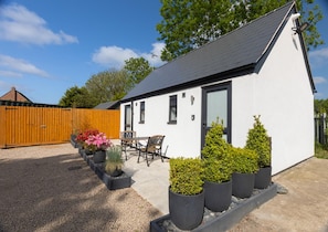 A single-story white house with a dark roof, a wooden fence, and a patio with a table and chairs. - Cosy Twin or Double Studio Near Shearsby, England (Lutterworth)