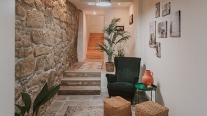 A staircase leading to a wooden floor, a green armchair, a woven pouf, and a terracotta pot on a small table. - Casa Farrapos (Porto)