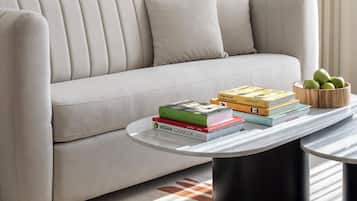 A modern living room with a sofa, a coffee table with books, and a framed abstract painting.