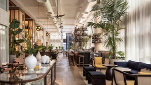 A modern bar area with wooden flooring, bar stools, and a variety of plants. - The George Tel Aviv (Tel Aviv)