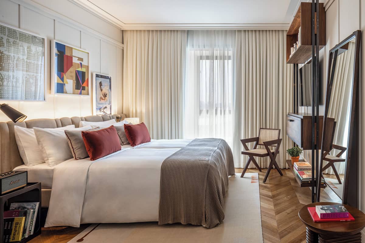 A modern hotel room with a large bed, two bedside tables, a desk, and a chair.