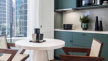 A modern kitchen with teal cabinets, a white countertop, and a round dining table with two chairs.