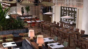 A spacious restaurant with multiple dining areas, including a long communal table and several smaller tables.