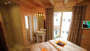 Una habitación de cabaña de madera con una cama, un baño con lavabo y una ducha.