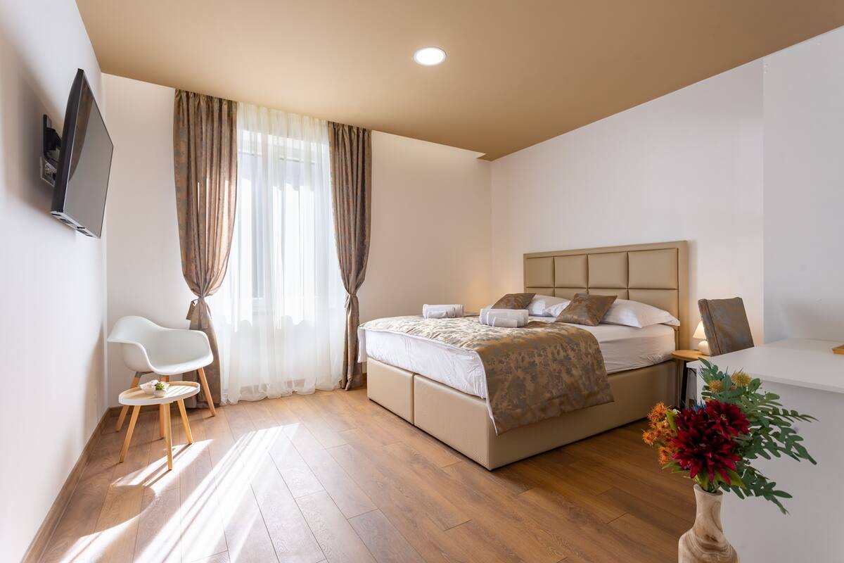 A modern hotel room with a bed, a desk, a chair, and a TV.