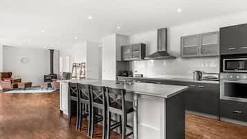 A modern kitchen with a central island, stainless steel appliances, and a wood floor.