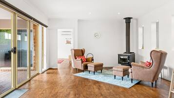 Ein modernes Wohnzimmer mit Kamin, Ledersesseln und einer Glastür zum Außenbereich.