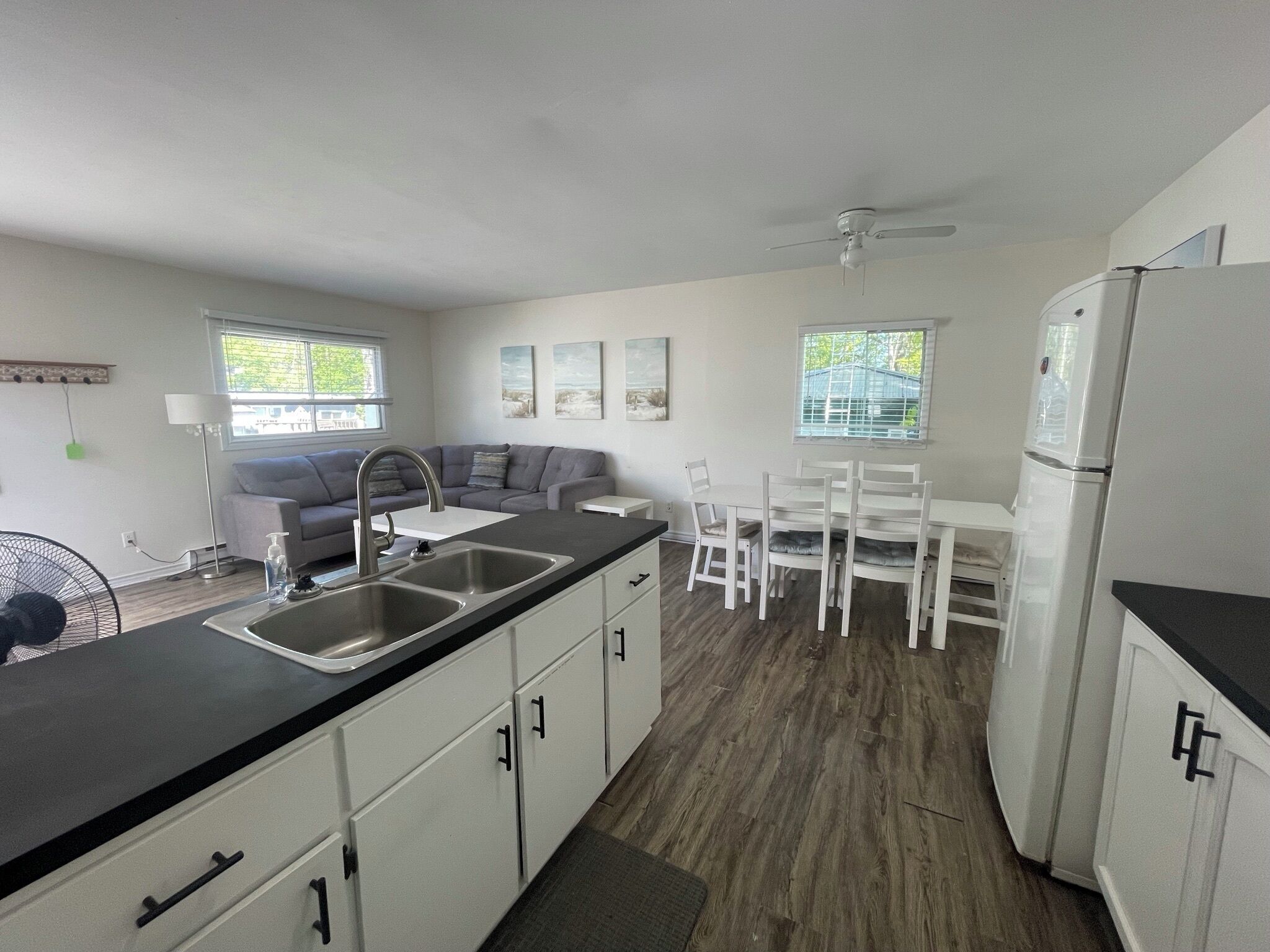 A modern kitchen with a dining area, a gray sofa, and a white refrigerator.
