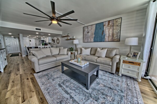 A spacious living room with a dark coffee table, beige sofas, and a large abstract painting on the wall.