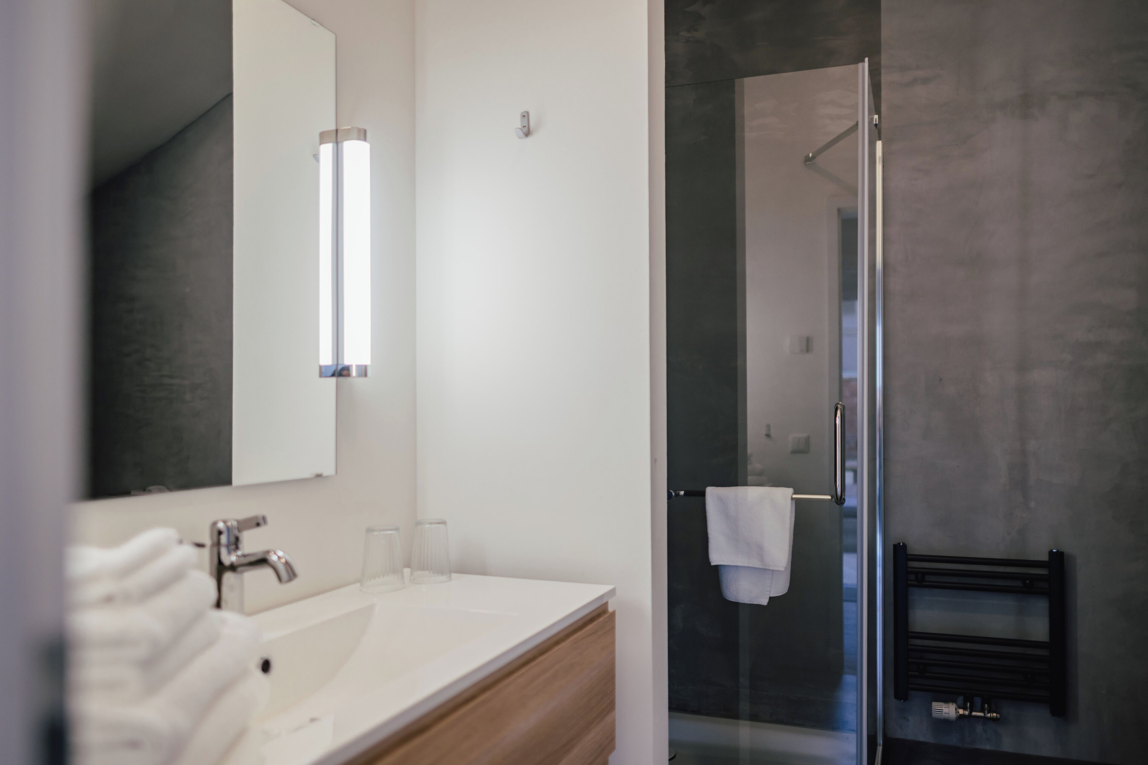 Een moderne badkamer met een witte wastafel, een spiegel en een douchecabine van glas.