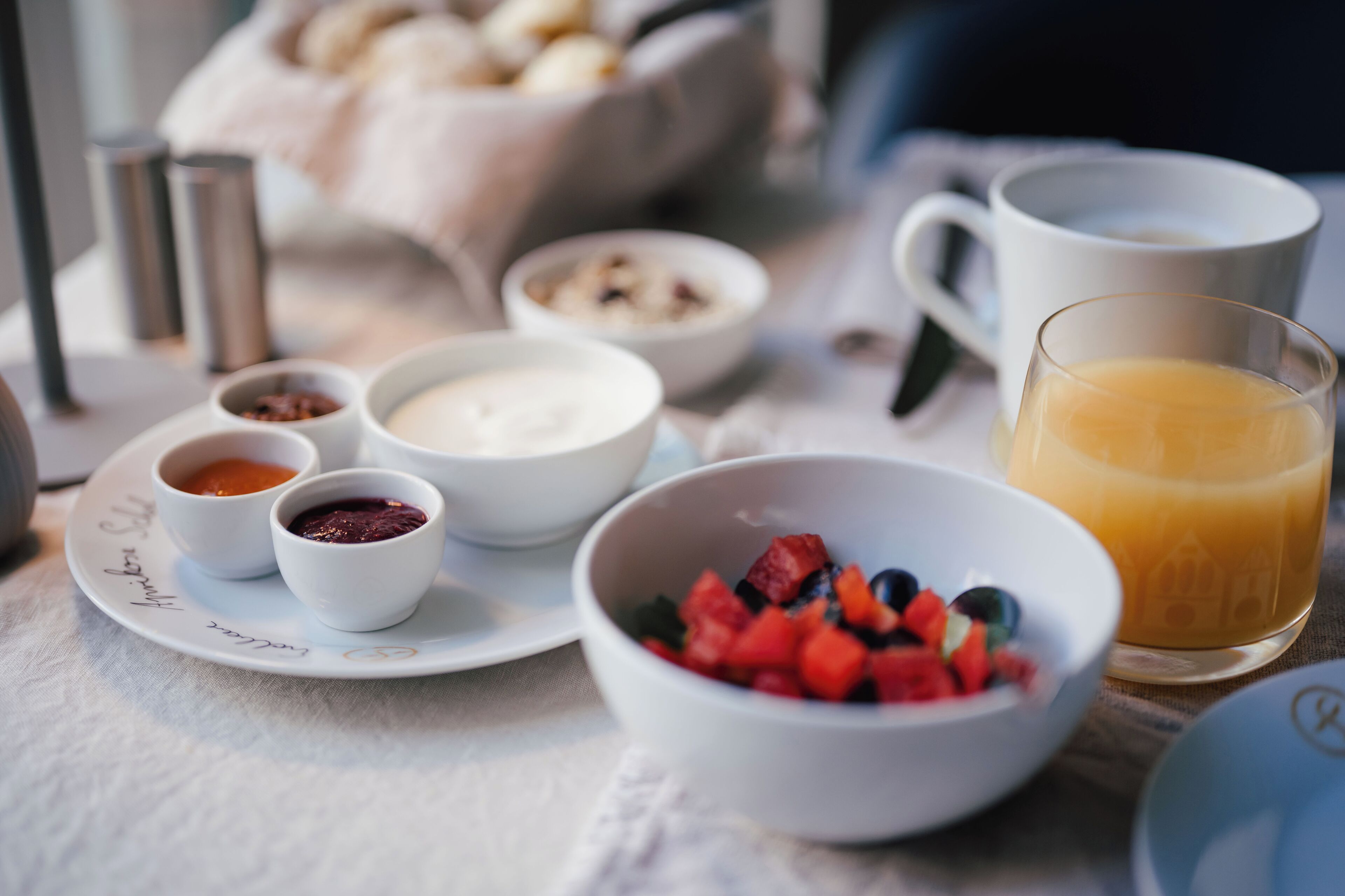 Un desayuno con diversos platos y un vaso de jugo de naranja sobre una mesa.