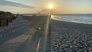 A beach with rows of numbered beach huts and a wooden boardwalk leading to the water.