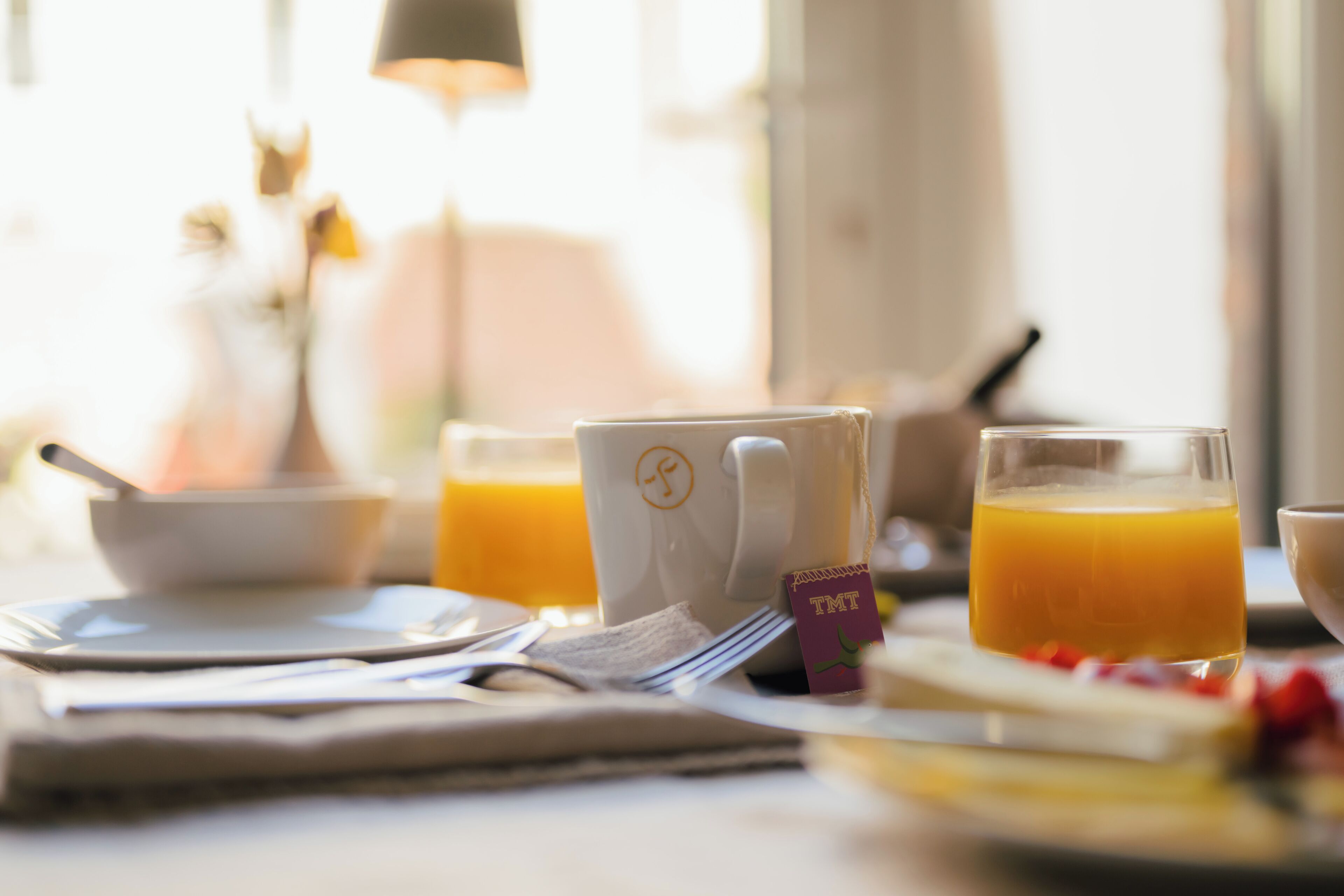 Een ontbijttafel met een kop, een glas sinaasappelsap en een kom.