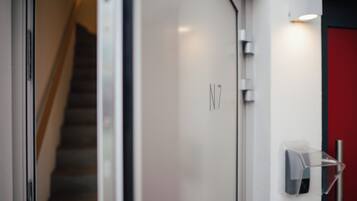 A modern interior with a staircase, a door labeled "N7", and a wall-mounted light fixture.