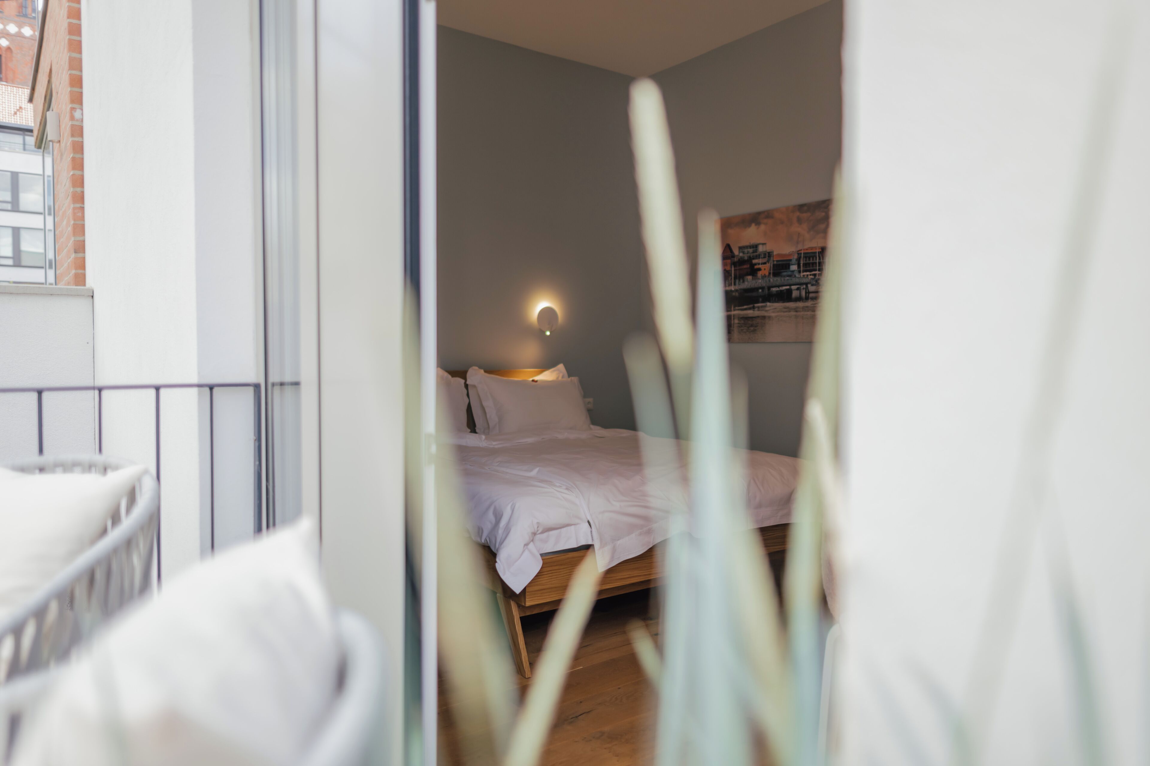 A bedroom with a bed, bedside lamp, and a view of the city through a window.
