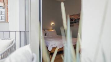 A bedroom with a bed, bedside lamp, and a view of the city through a window.