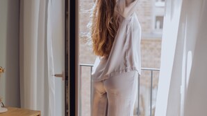 A person standing by a sliding glass door with a view of a brick building.