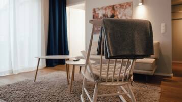 Een moderne woonkamer met een witte schommelstoel, een klein wit tafeltje en een beige bank.