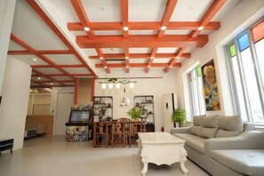 A spacious living room with a high ceiling, a dining area with a table and chairs, and a sofa.