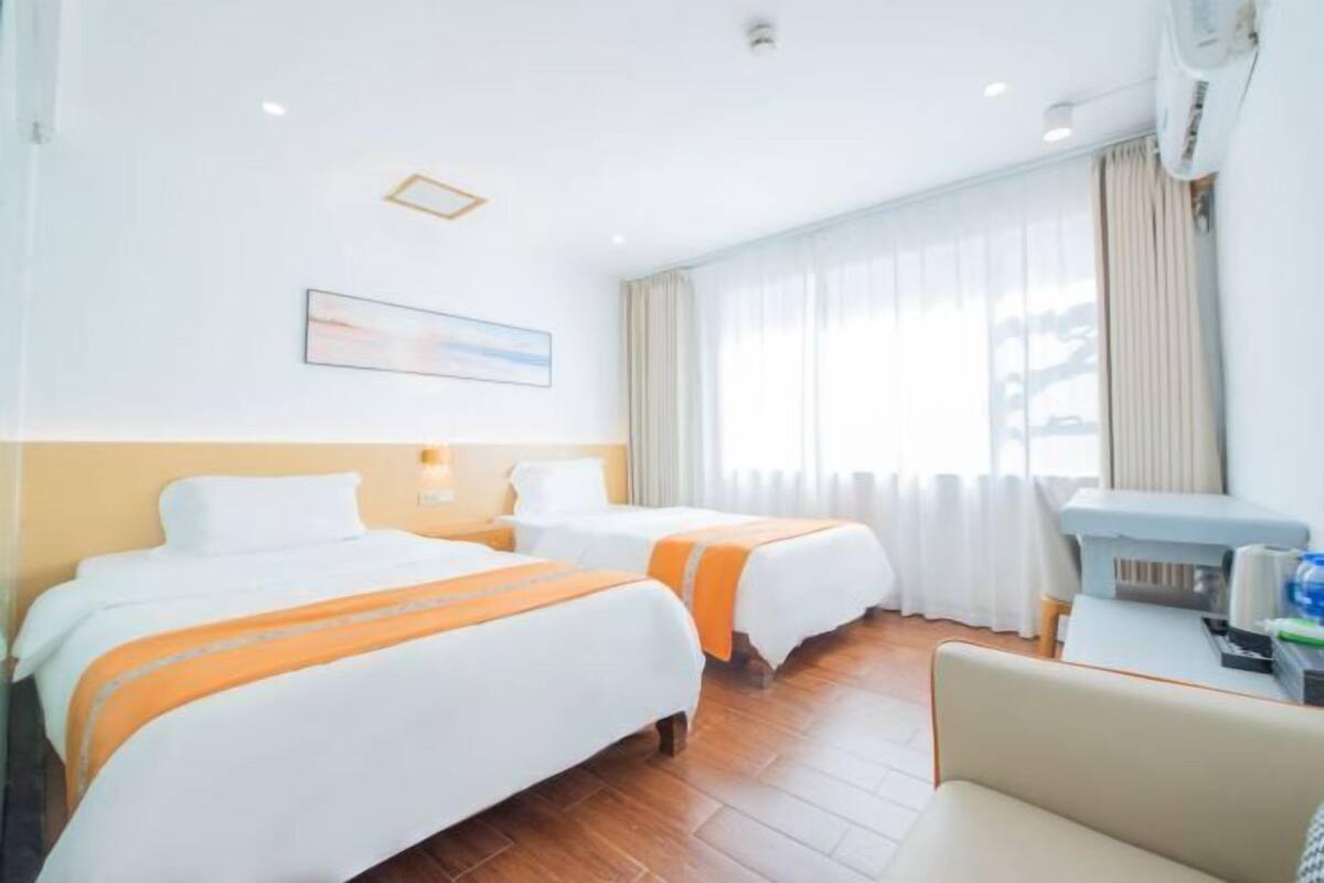 Habitación de hotel con dos camas, un escritorio y una ventana con cortinas.