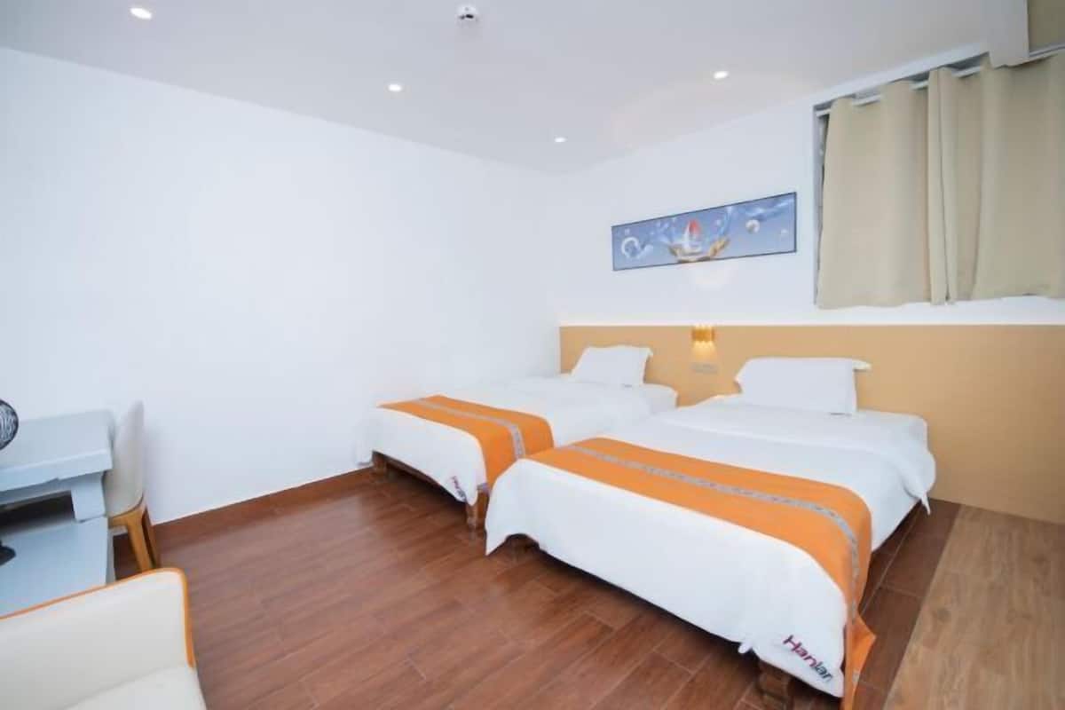 Habitación de hotel con dos camas, un escritorio y una silla.