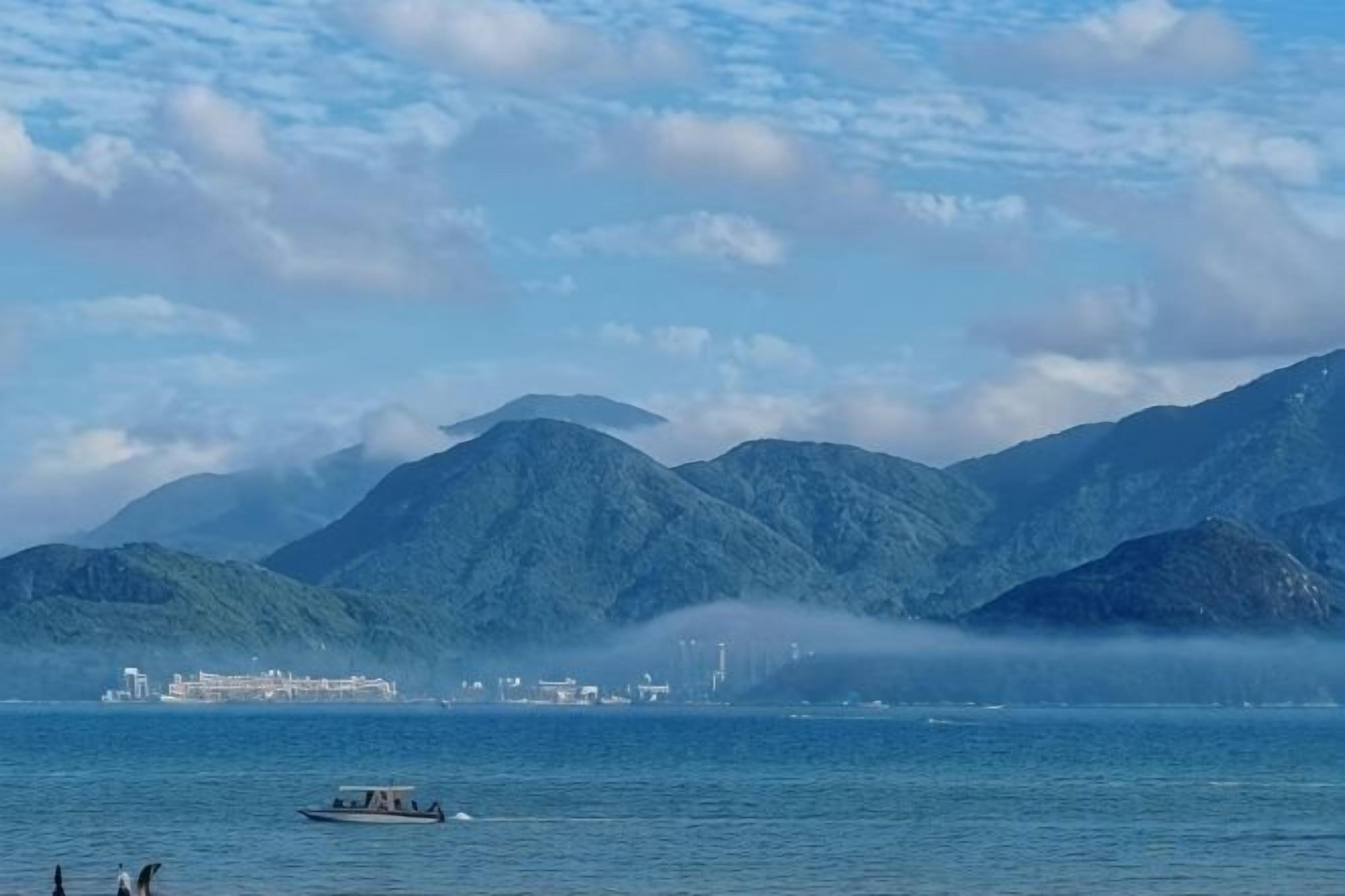 A body of water with mountains in the background and a boat in the foreground.