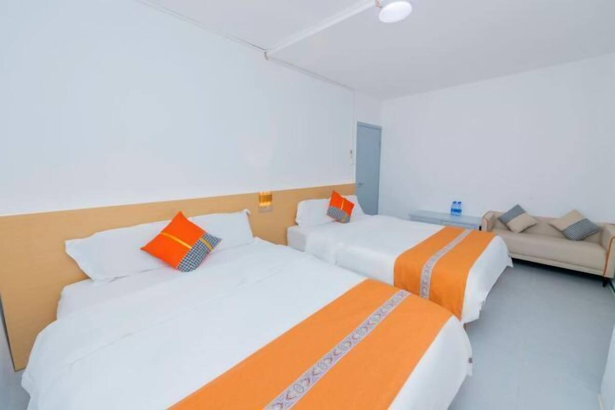 Habitación de hotel con dos camas, un sofá y una pequeña mesa.