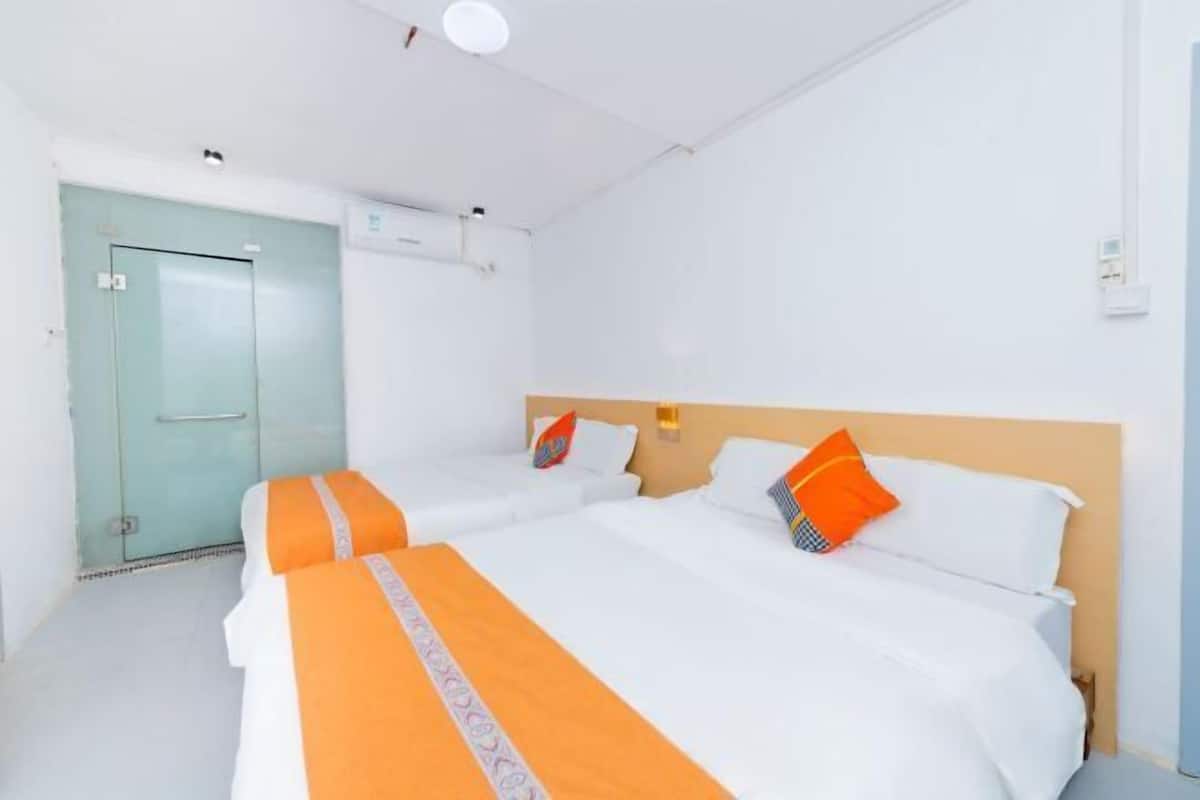Habitación de hotel con dos camas, una puerta azul claro y una pared blanca.