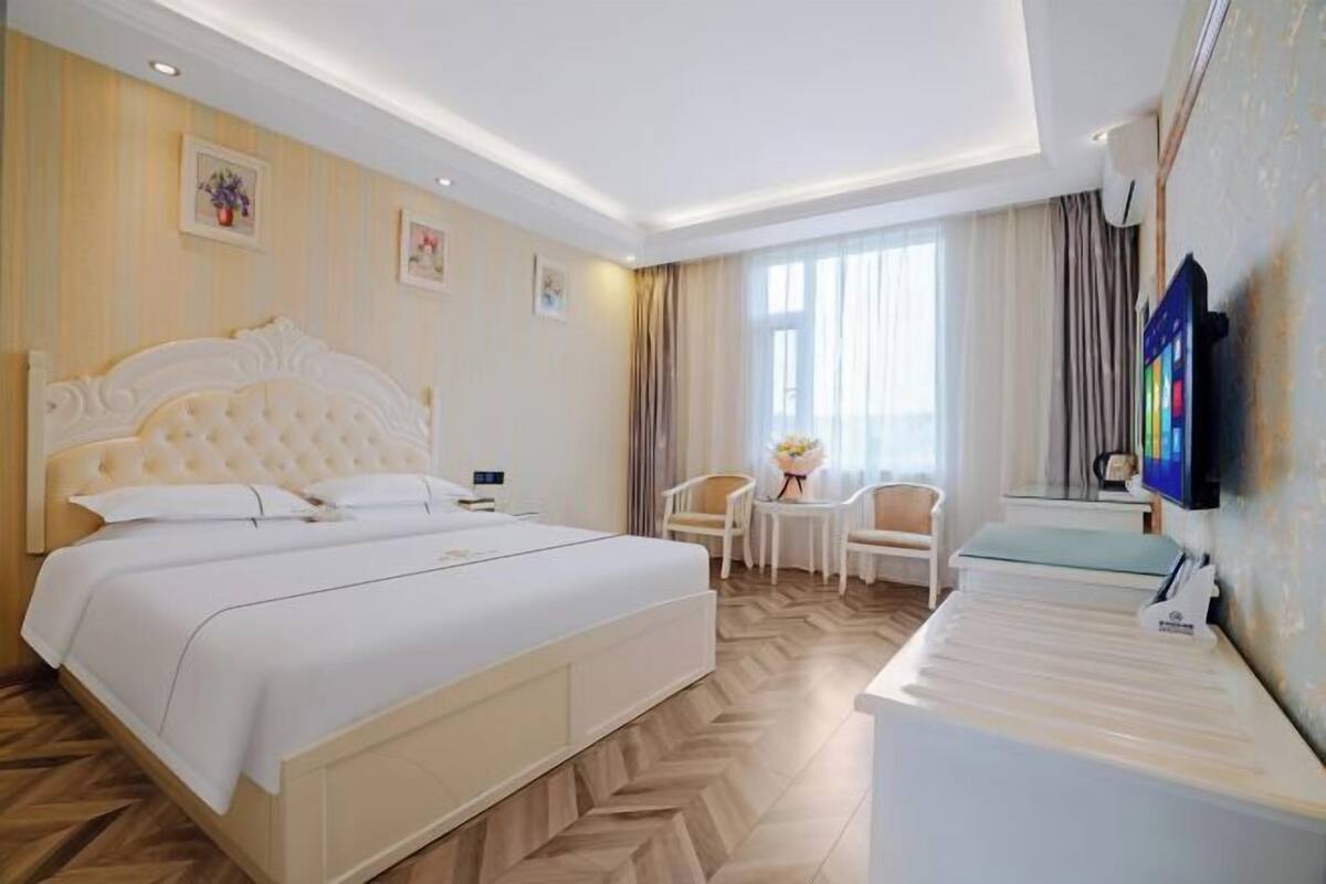 A hotel room with a large bed, a small table, a chair, and a television.