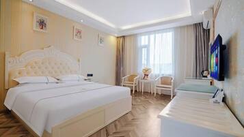 Habitación de hotel con una cama grande, una mesita pequeña, una silla y un televisor.