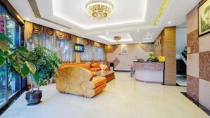A hotel lobby with a reception desk, a sofa, and a large potted plant. - Zihong Hotel (Yuxi)
