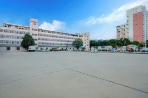 Un edificio grande con varios pisos, un estacionamiento y varios vehículos.